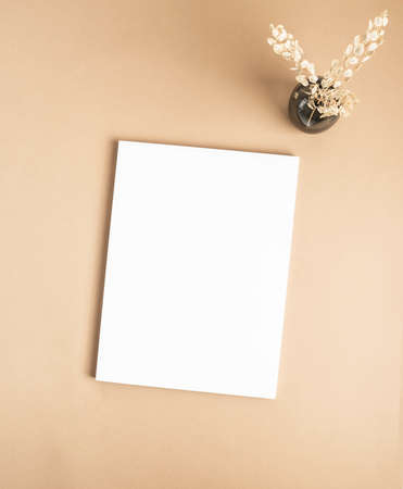 White magazine cover mockup and dry grass in vase on beige background. top view. Copy space