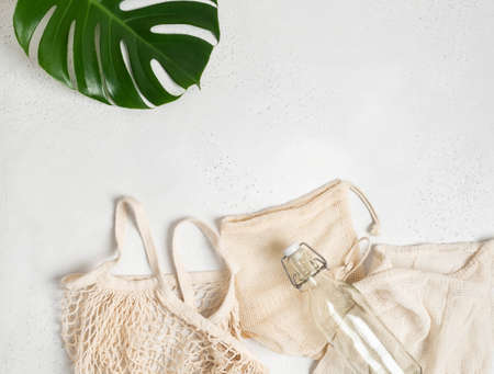 Various bags with drawstring, string bag eco sack made from natural cotton fabric cloth and glass bottle flat lay on light gray background. Top view. Copy spaceの写真素材