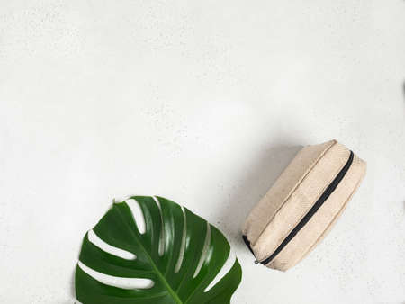 Eco textile cosmetic bag and green monstera leaf on gray background. Top view. Copy spaceの写真素材