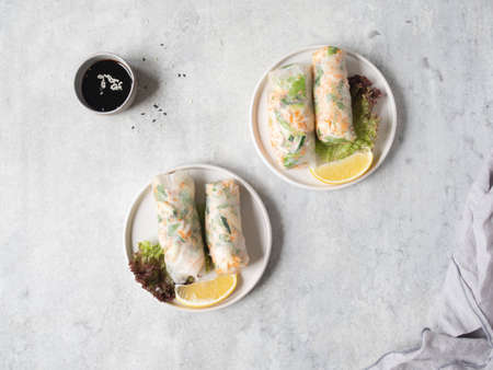 Vietnamese spring rolls with salad, sauce, crab, and noodles on plates and sause in bowl on gray background. top view. copy spaceの写真素材