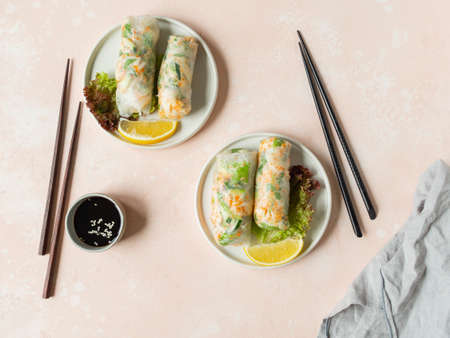 Vietnamese spring rolls with salad, sauce, crab, and noodles on plates and sause in bowl on pink...