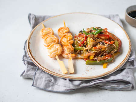 Prawn Skewer and asian vegetables stir fry on white plate.の写真素材