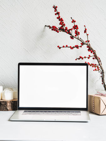 Stylish modern Christmas background. Laptop empty screen and season decoration against the white wall. Front view. Copy spaceの写真素材