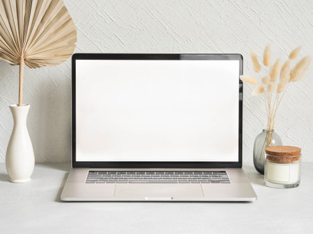 Laptop empty screen and different decoration against the white wall. Stylish home office. Front view. Copy spaceの写真素材