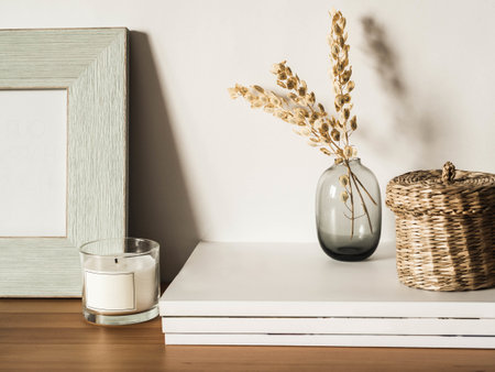 Home still life of dry flowers in vase, straw box, glass candle and magazines on wooden table. Copy space. Front viewの写真素材