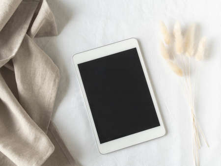 Empty black screen tablet mock up and fluffy dried flowers on white textured background. Flat lay. Top view. Copy spaceの写真素材