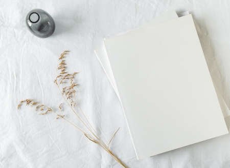 Empty blank white magazine cover mock up, vase and dried grass on light texture background. Flat lay. Top view. Copy spaceの写真素材