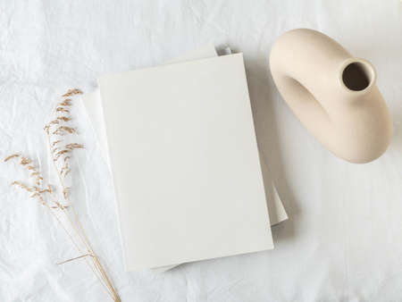 Empty blank white magazine cover mock up, vase and dried grass on light texture background. Flat lay. Top view. Copy spaceの写真素材