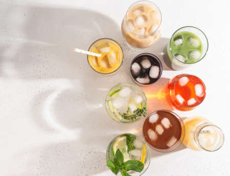 Various refreshing non-alcoholic drinks in glasses with ice. Different juice, homemade lemonade, iced coffee, iced fruit tea and smoothies on white background. Copy space. top viewの写真素材