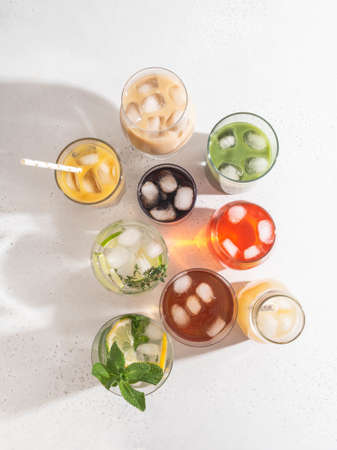 Various refreshing non-alcoholic drinks in glasses with ice. Different juice, homemade lemonade, iced coffee, iced fruit tea and smoothies on white background. Copy space. top viewの写真素材