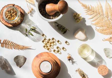 Organic natural product - oils and various dry plants for health on white background in the sunlight. Herbal alternative medicine and aromatherapy. Top viewの写真素材