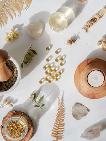 Organic natural product - oils and various dry plants for health on white background in the sunlight. Herbal alternative medicine and aromatherapy. Top viewの写真素材