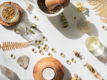 Organic natural product - oils and various dry plants for health on white background in the sunlight. Herbal alternative medicine and aromatherapy. Top viewの写真素材