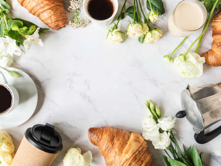 Flat lay frame of cups of coffee, flowers and croissantの写真素材