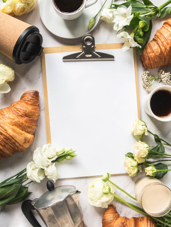 Flat lay frame of cups of coffee, flowers, croissants and clipboard with blank sheet for menu entryの写真素材