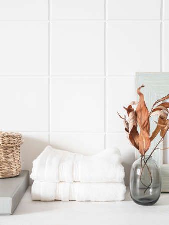 White bath background front view with glass vase, white towels and decor on white shelf and wall tiles. Front view. Copy spaceの写真素材