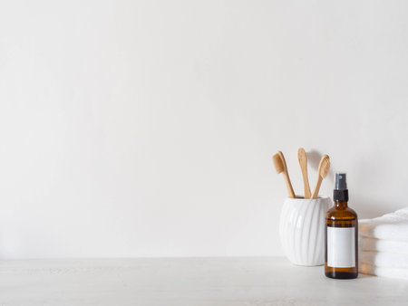 Amber glass bottle with white lable, bamboo toothbrushs and white towels on white background. Front view. Minimal bath background. Copy spaceの写真素材