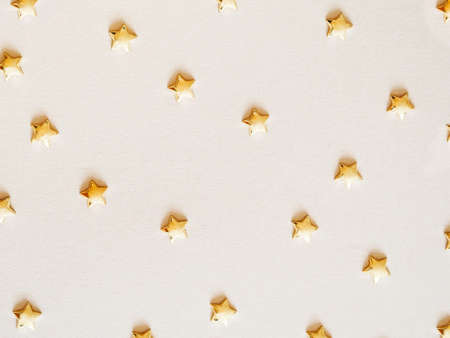 Party shiny decoration pattern - golden stars in the form of confetti on beige background flat lay. Top viewの写真素材