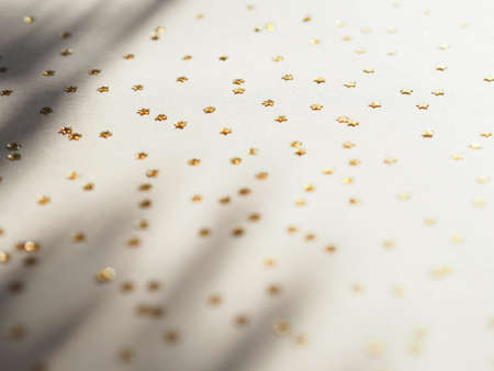 Party shiny decoration pattern - golden stars in the form of confetti with shadow on beige background flat lay. Top viewの写真素材