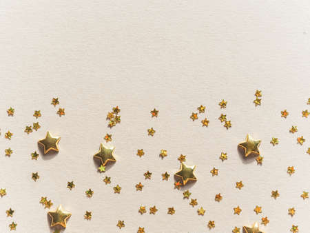 Party shiny decoration pattern - golden stars various size in the form of confetti on beige background flat lay. Top view, copy spaceの写真素材