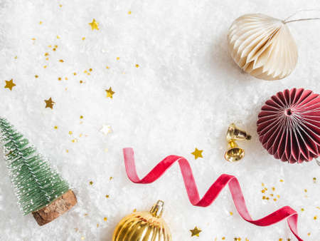 Flat lay frame various green, red and gold christmas decor on artificial snow background. Holiday...
