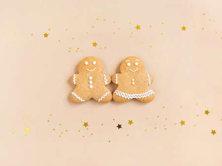 Happy New Year or Christmas card, gingerbread couple - man and woman and golden shine stars on beige background. Happy family concept Top view. Flat layの写真素材