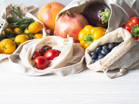 Fresh vegetables and fruits in eco cotton bags on table in the kitchen. Zero waste shopping concept. Front view. Copy space.の写真素材