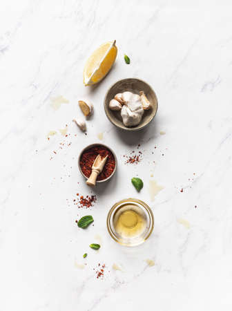 Preparation salad dressings, - chili spices, oil, lemon juice and garlic on white marble background....