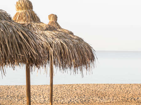 Straw umbrellas on empty seaside beach. Beach holiday conceptの写真素材