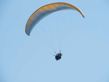Paragliding flight. Two undefined people are paragliding in the sky and taking selfies or filming a video about the flightの写真素材