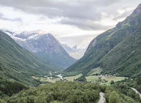 Norwegian landscape with green valley between mountains with snow peaks. View of the fjord with a green valley surrounded by mountains.の写真素材