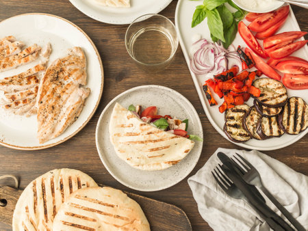 Pita with grilled vegetables, paprika, raw onion, eggplant, tomato, chicken and basil with sauce. A table served for dinner.の写真素材