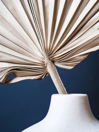 Round stylish ceramic vase with dried palm leaf. dark blue background. front view. copy spaceの写真素材