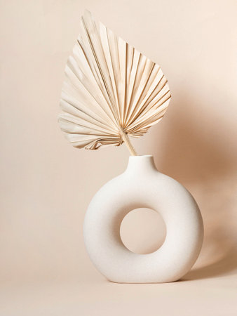 Round stylish ceramic vase dried with palm leaf casting shadows on the wall. Beige background. front view. copy spaceの写真素材