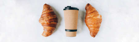 Croissants with coffee to go in eco cup, take away breakfast banner. Flat lay, njp view, copy spaceの写真素材