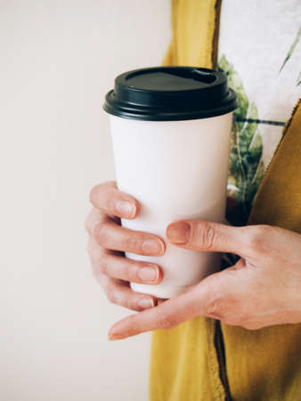 Female hands holding paper cup of coffeeの写真素材