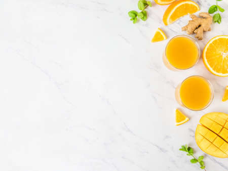 Mango orange juice smoothie in glasses on white marble background. fresh healthy drink. Top view, copy space, flat layの写真素材