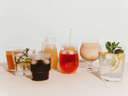 Various refreshing non-alcoholic drinks in glasses with ice. Different juice, homemade lemonade, iced coffee, iced fruit tea and smoothies on light background. copyspace. front viewの写真素材