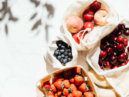 Fresh berries in bags and box on the table in sunlight. Purchases made at the local store on the kitchen tableの写真素材