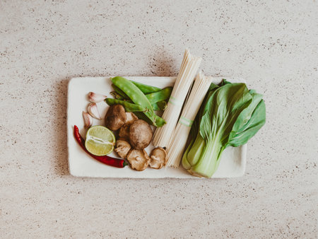 Cooking ingredients for Asian dishes: bok choy, shiitake mushrooms, lime, soba, green peas and garlic on plate on a gray concrete background, top view. copy spaceの写真素材