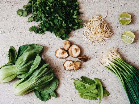 Cooking ingredients for Asian dishes: bok choy, shiitake mushrooms, sprouts, lime, coriander, green peas and green onions on a gray concrete background, top viewの写真素材