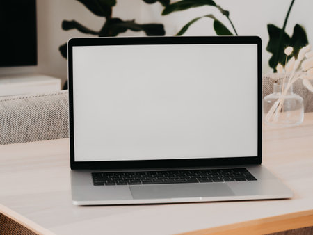 Laptop with blank screen on wooden table in home interior. Workplace mockup concept. Home office background with copy space mock up laptopの写真素材