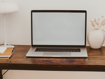 Laptop with blank screen on wooden table in home interior. Workplace mockup concept. Home office background with copy space mock up laptopの写真素材
