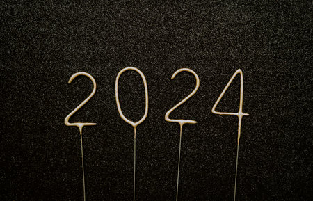 Golden sparklers in the form of the numbers 2024 on a black background. New Year celebration...