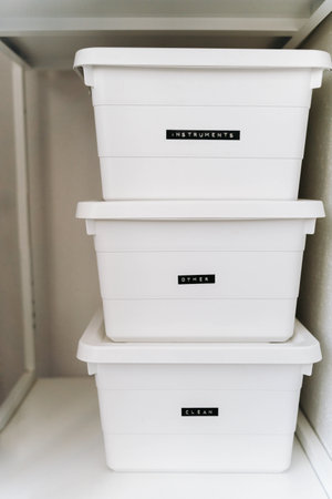 Minimal white storage boxes stacked on shelf with labels for organization. Clean home storage...