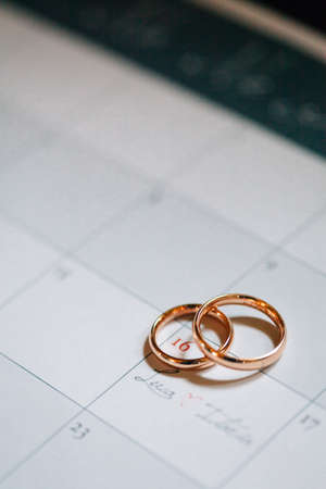 Two golden wedding rings lay on calendar wedding day date. Preparation for weddings conceptの写真素材