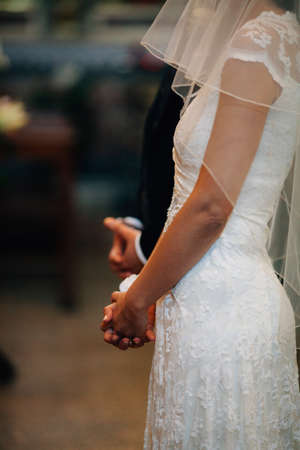 Bride and groom stand together side by side on wedding ceremony in church with copy paste backgroundの写真素材