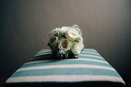 Close up bridal rose bouquet on retro chair with blank gray wall backgroundの写真素材