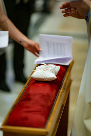 Wedding rings on white cushion on wedding ceremony by alter in churchの写真素材