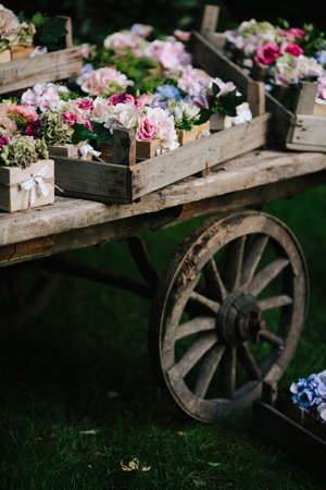 Close up retro style wooden carriage with wedding bouquet flowers displayed on trays outdoors in summer greenery outdoorsの写真素材